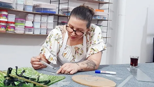 Sibel Ahmetler atölyesindeki masada cam keserken